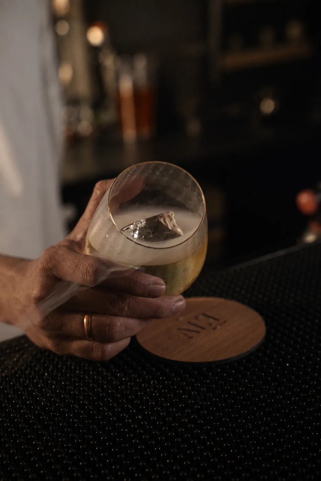 A clear cocktail served on an ALT coaster at the bar