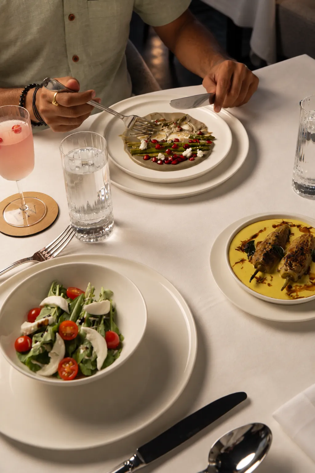 Guests sharing plates and a pink cocktail at a white table