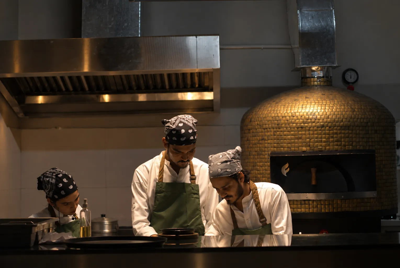 Chefs at work in front of the gold-tiled wood-fired oven