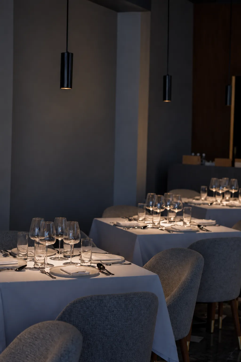 Long rows of set tables under black pendant lights