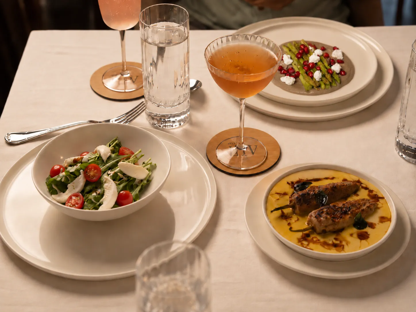Asparagus, salad, a stuffed chilli in kadhi and two cocktails shared on one table
